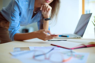 Ofis masasında oturan ve cep telefonuyla konuşan genç ve güzel bir iş kadını. İş kadını