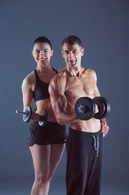 Atletik erkek ve kadın ile bir dumbells. Kişisel fitness eğitmeni. Kişisel eğitim.
