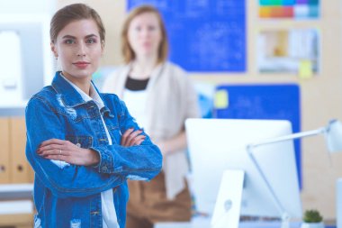 İki genç kadın masada enstrümanlar, planlar ve dizüstü bilgisayarlarla oturuyor..