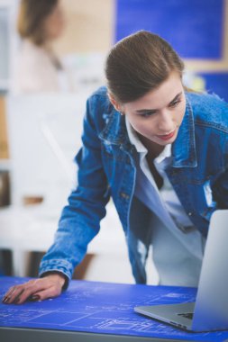 Masanın yanında duran iki genç kadın enstrüman, plan ve dizüstü bilgisayarla.