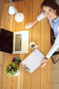 Masasında oturan ve elinde bir fincan kahveyle rahatlamış genç bir kadının portresi. İş kadını. İşyeri