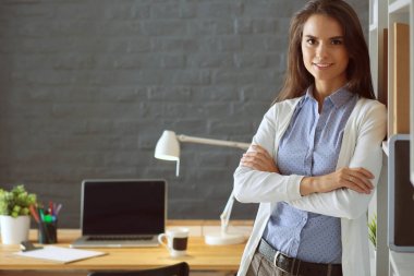 Dizüstü bilgisayarının yanında duran genç bir kadın.