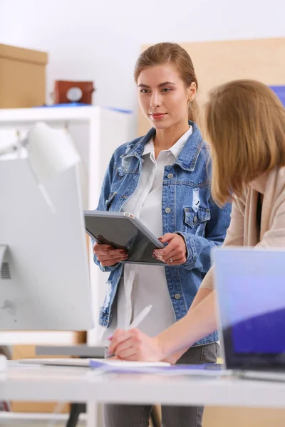 Zwei junge Frauen stehen neben Schreibtisch mit Instrumenten, Plan und Laptop. — Stockfoto