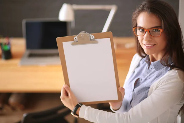 Jeune femme debout près du bureau avec ordinateur portable tenant dossier et tasse de café. En milieu de travail. Femme d'affaires. — Photo