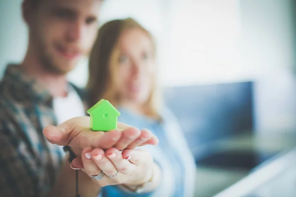 Casa modello in mano a una coppia, in piedi in una nuova casa. Modello di casa . — Foto Stock