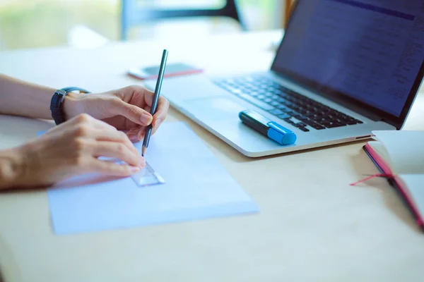 Mujer joven sentada en el escritorio con instrumentos, plan y portátil. Mujer joven — Foto de Stock