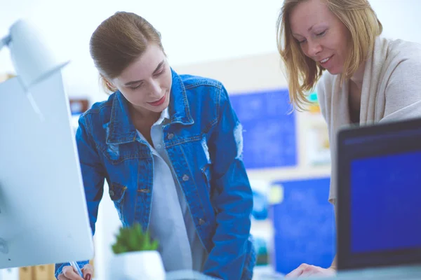 Two young woman standing near desk with instruments, plan and laptop. — Stock Photo, Image