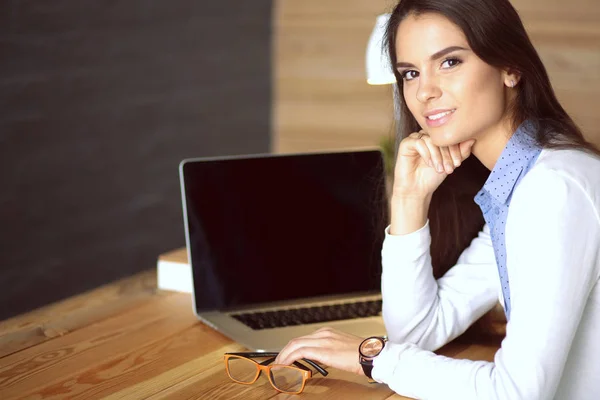 Jeune femme travaillant assise à un bureau. — Photo