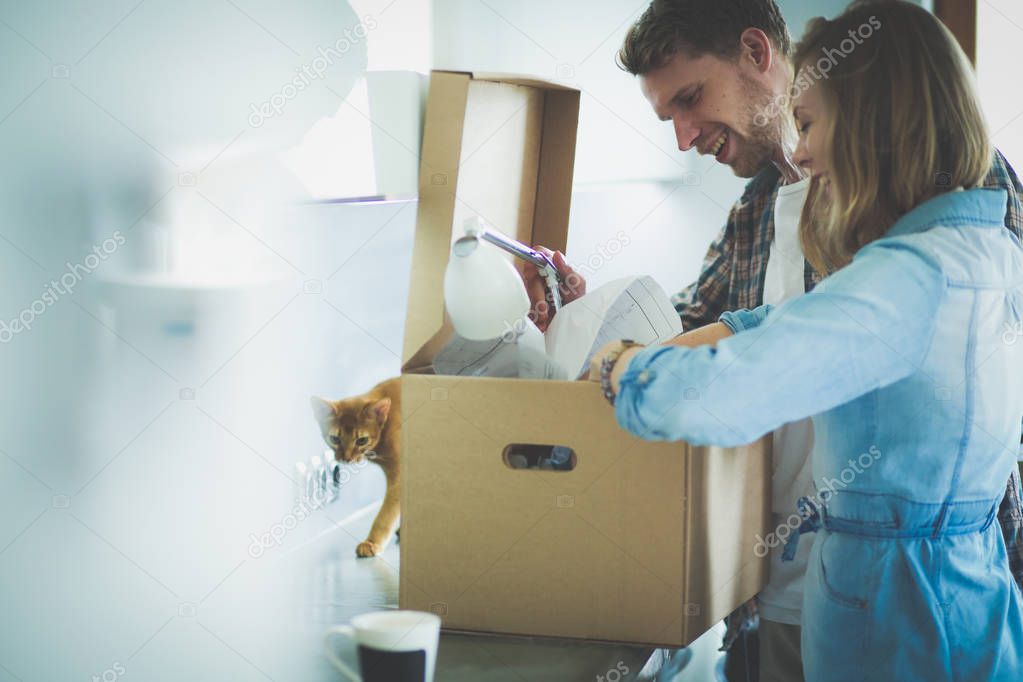 Young couple carrying big cardboard box at new home.Moving house. Young couple