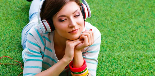 Γυναίκα ακούγοντας τη μουσική που βρίσκεται στο καταπράσινο γρασίδι — Φωτογραφία Αρχείου