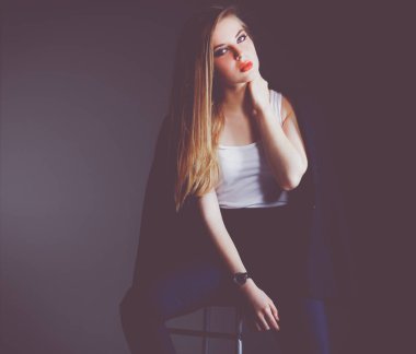 Genç bir kadın sandalyede oturuyor.