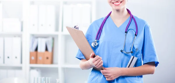 Médico sonriente con una carpeta en uniforme de pie en el hospital — Foto de Stock