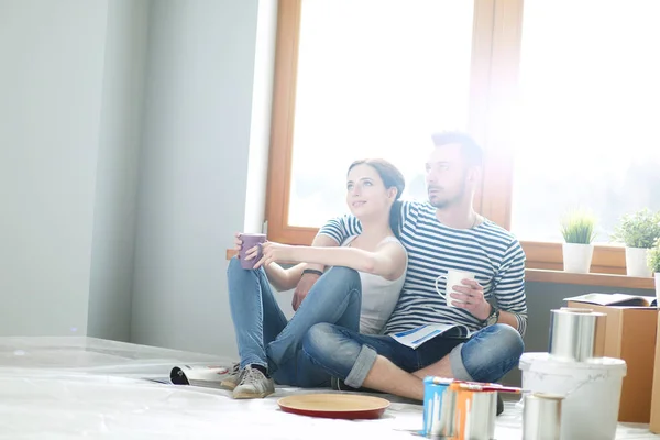 Retrato feliz sorrindo jovem casal pintura parede interior da nova casa. Casal jovem — Fotografia de Stock