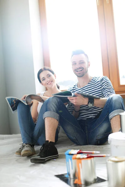 Portret vrolijk glimlachend jong stel schilderen interieur muur van nieuw huis. Jong stel — Stockfoto