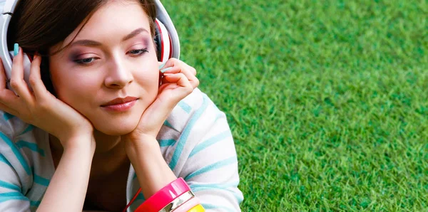 Donna che ascolta la musica sdraiata sull'erba verde — Foto Stock