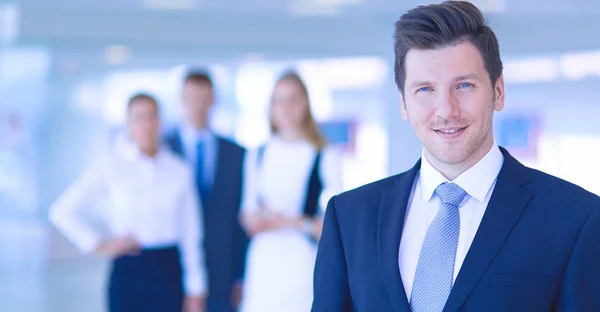 Portret van jonge zakenman in kantoor met collega's op de achtergrond — Stockfoto