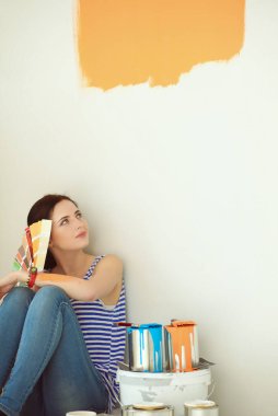 Kadın seçerek boya rengi renk örneği yeni ev ahşap yere oturmak için. Kadın evde