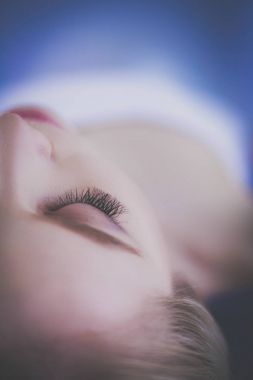 Masaj masasında uzanmış gözleri kapalı rahatlayan genç bir kadın. - Kadın. Spa salonu