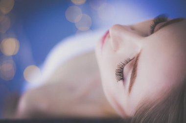 Masaj masasında uzanmış gözleri kapalı rahatlayan genç bir kadın. - Kadın. Spa salonu