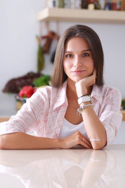 Mutfakta masada oturan genç bir kadın.