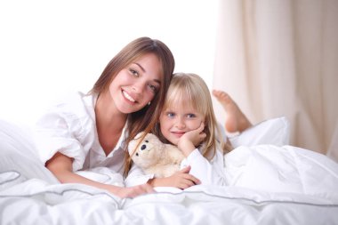 Mutlu sevgi dolu aile. Anne ve kızı çocuk kızı yatakta oynarken