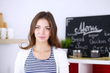 Mutfakta masanın yanında duran genç bir kadın.