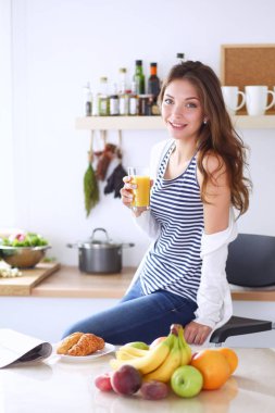 Genç bayan mutfakta masanın yanında oturuyor.