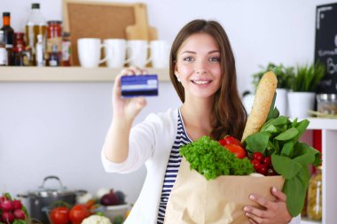 Bakkal alışveriş çantası sebze ve kart tutan genç kadın