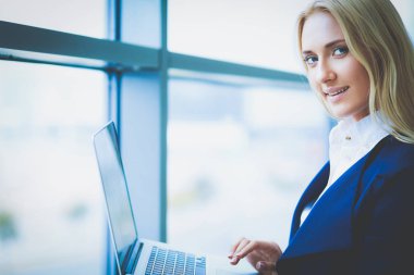 Dizüstü tutarak ofis pencere karşı ayakta işkadını