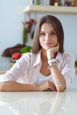 Mutfakta masada oturan genç bir kadın.