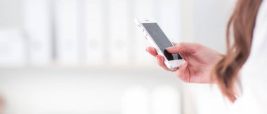 İş kadını ofiste akıllı telefonla mesaj gönderiyor.