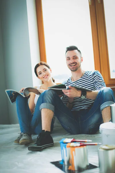 Retrato feliz sorrindo jovem casal pintura parede interior da nova casa. Casal jovem — Fotografia de Stock