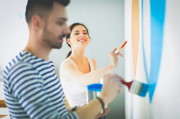 Portrait of happy smiling young couple painting interior wall of new house. young couple — Stock Photo, Image