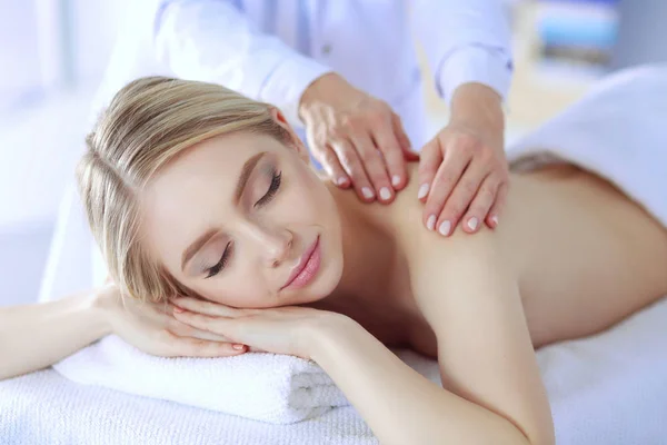 Mujer joven acostada en una mesa de masaje, relajándose con los ojos cerrados. Una mujer. Salón de spa —  Fotos de Stock