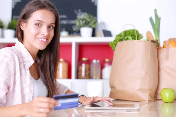 Smiling woman online shopping using tablet and credit card in kitchen — Stock Photo, Image