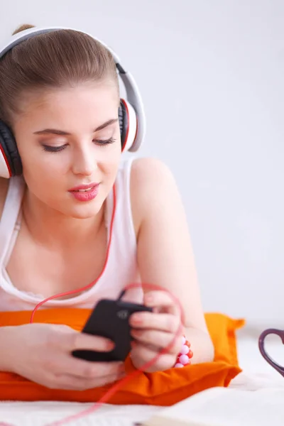 Jonge vrouw liggend op verdieping en luisteren naar muziek — Stockfoto