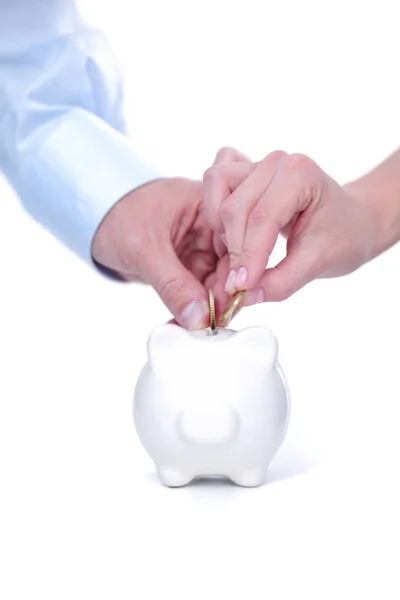 Una mano sostiene una moneda en la caja de dinero del banco de monedas de cerdo fondo blanco aislado —  Fotos de Stock