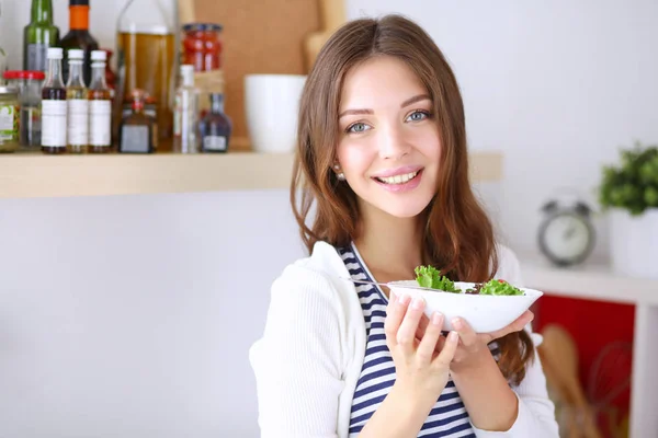 Ung kvinna äter sallad och håller en blandad — Stockfoto