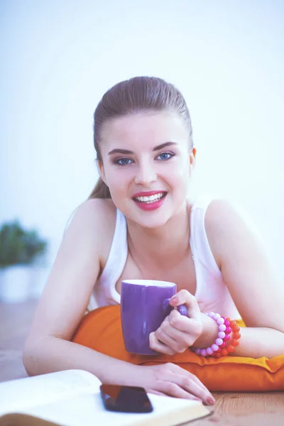 Smiling young woman lying on a white floor with pillow — Stock Photo, Image