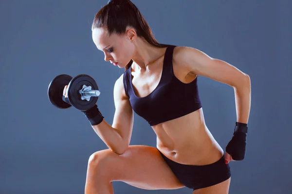 Atletisk kvinna som pumpar upp muskler med hantlar — Stockfoto