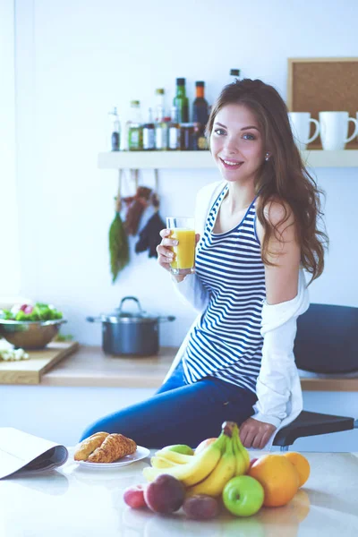 Genç bayan mutfakta masanın yanında oturuyor.