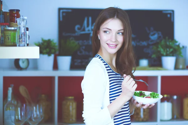 Junge Frau isst Salat und hält eine gemischte — Stockfoto