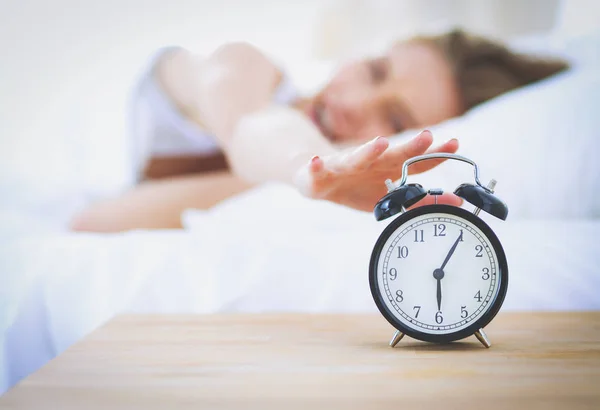 Young sleeping woman and alarm clock in bedroom at home. Young sleeping woman. Stock Image