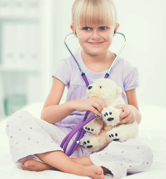 La bambina sta esaminando il suo orsacchiotto usando lo stetoscopio — Foto Stock