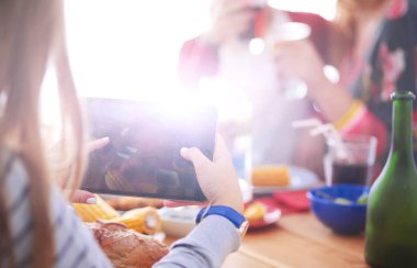 Ahşap masada otururken birlikte yemek yiyen bir grup insanın üst düzey görüntüsü. Masada yemek var. İnsanlar fast food yiyor..