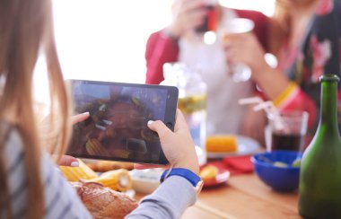 Ahşap masada otururken birlikte yemek yiyen bir grup insanın üst düzey görüntüsü. Masada yemek var. İnsanlar fast food yiyor..