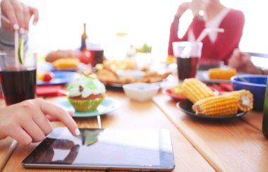 Ahşap masada otururken birlikte yemek yiyen bir grup insanın üst düzey görüntüsü. Masada yemek var. İnsanlar fast food yiyor..