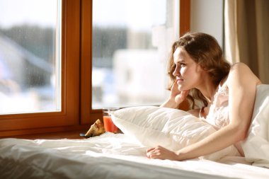 Pencere yakınındaki erken sabah yatakta yatan kadın.