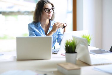 Ofis masasında dizüstü bilgisayarla oturan genç bir kadın. Genç bir kadın. Dizüstü bilgisayar