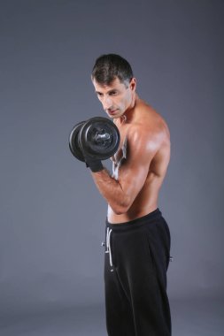 Yakışıklı kaslı adam dumbell ile çalışma dışarı. Kişisel fitness eğitmeni. Kişisel eğitim.